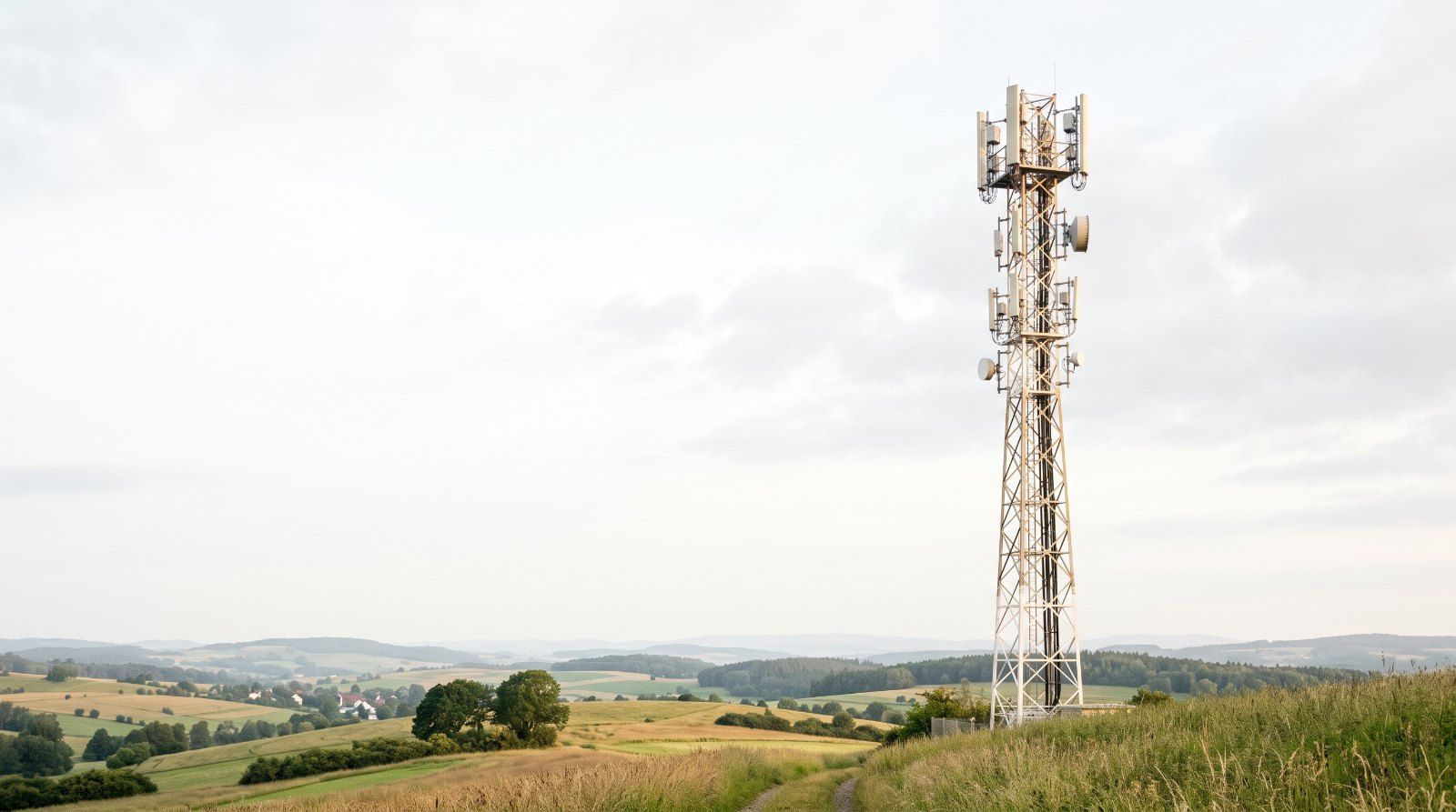 Mobilfunkmast in der Dämmerung über einer Mittelgebirgslandschaft